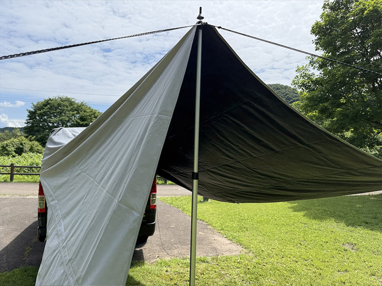 QUICKCAMPカーサイドタープを車のリアに展開しようとしている様子